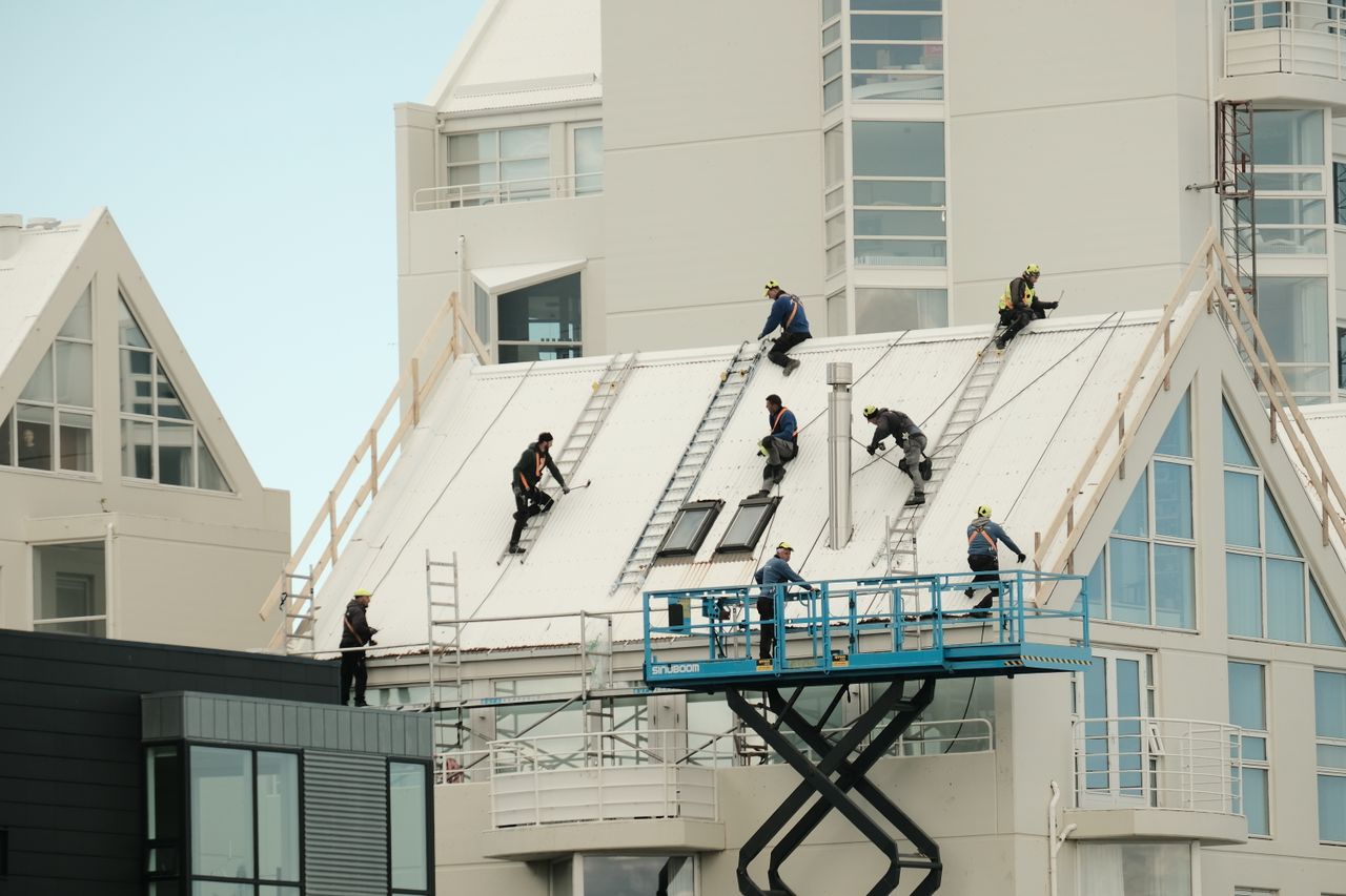 Mastering the First Impression: Your intriguing post title goes here Construction workers repairing a modern roof in Reykjavík, highlighting teamwork and safety.